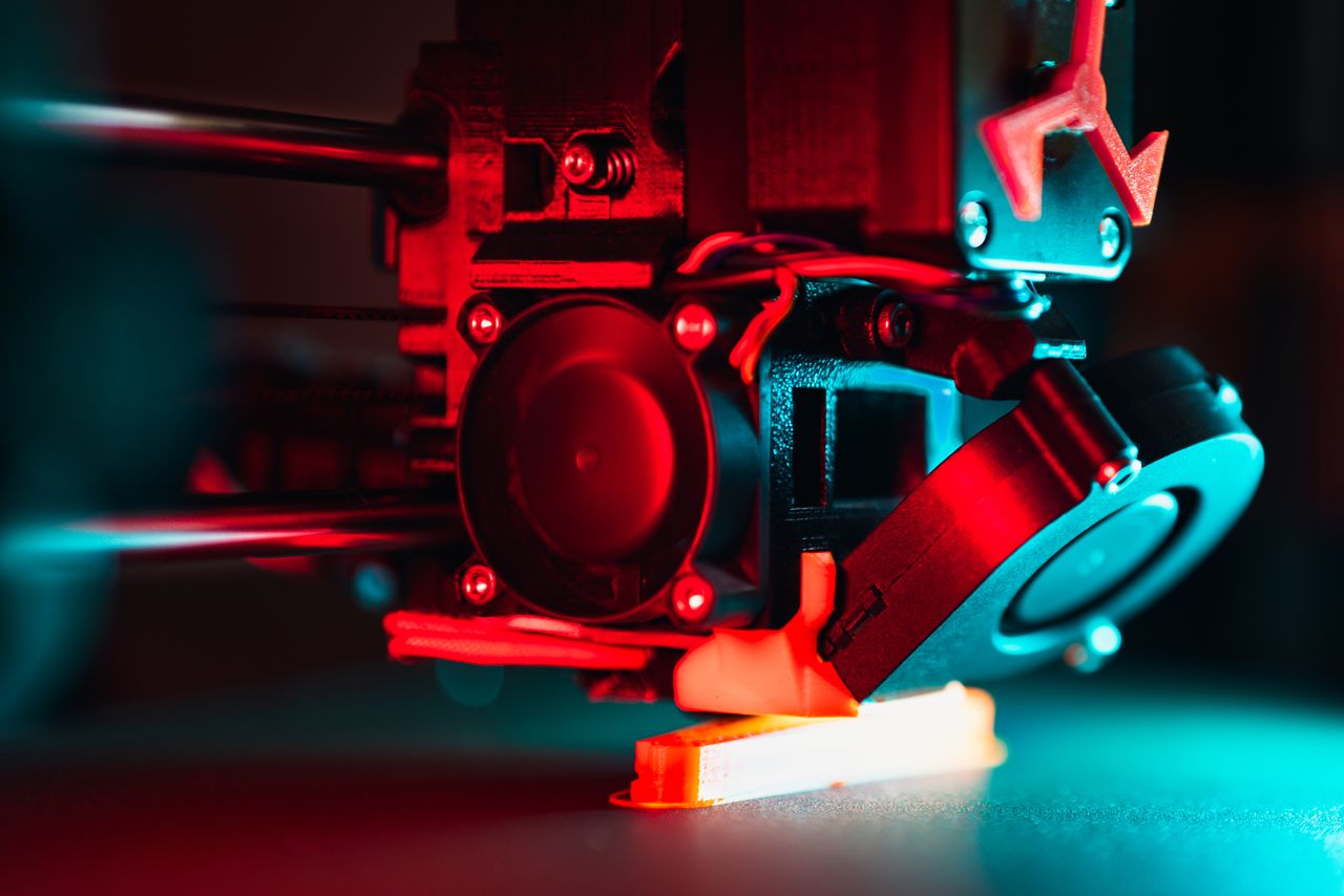 Vibrant close-up of a 3D printer creating a prototype with red and blue lights.